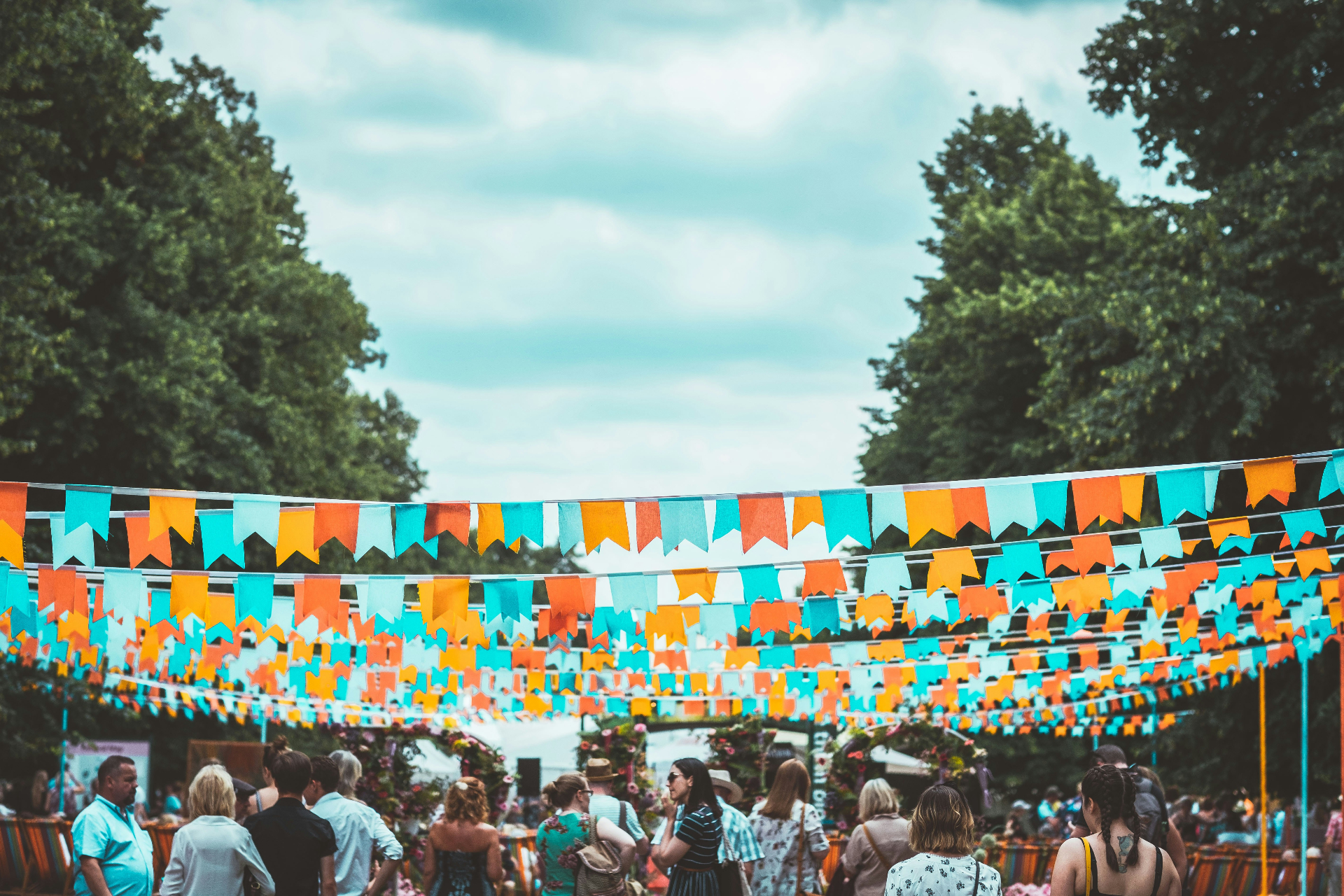 Colourful bunting flags above a busy outdoor festival crowd